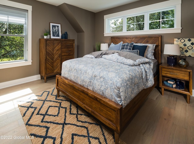 bedroom with multiple windows, light wood-style flooring, and baseboards