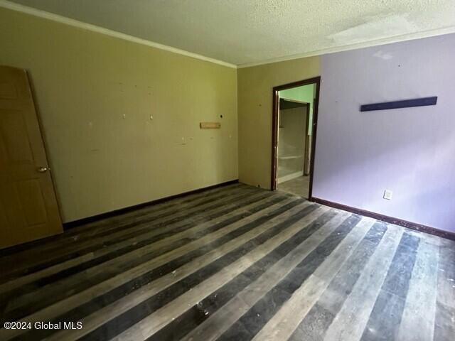 spare room featuring a textured ceiling, ornamental molding, and dark wood-type flooring