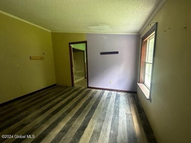 unfurnished room featuring crown molding, dark hardwood / wood-style flooring, and a textured ceiling