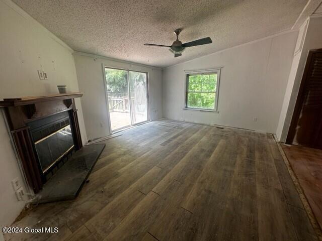 unfurnished living room featuring dark hardwood / wood-style flooring, a textured ceiling, a wealth of natural light, and lofted ceiling