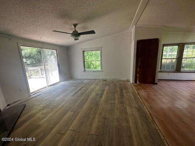 unfurnished room with a textured ceiling, ceiling fan, dark hardwood / wood-style floors, and vaulted ceiling