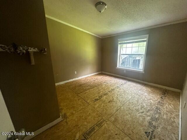 unfurnished room with a textured ceiling and ornamental molding