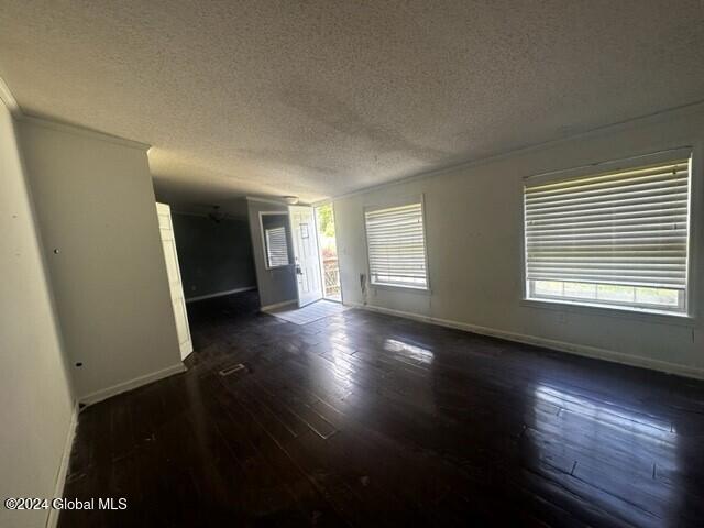 unfurnished room featuring plenty of natural light, dark hardwood / wood-style flooring, and a textured ceiling