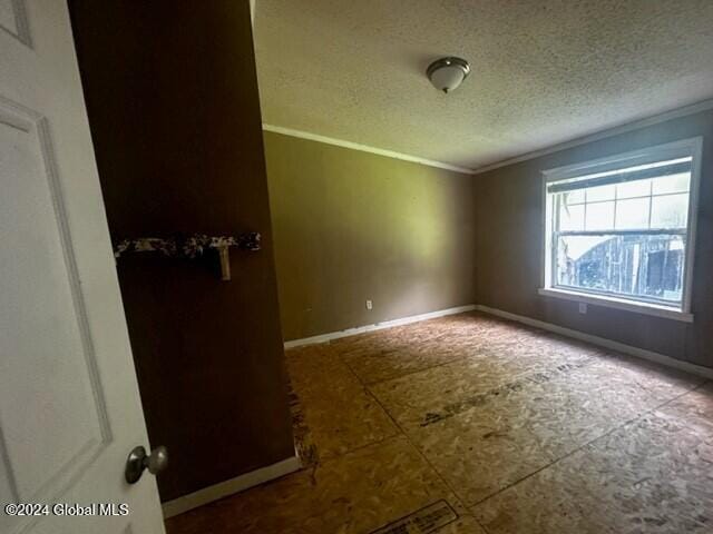 spare room featuring crown molding and a textured ceiling