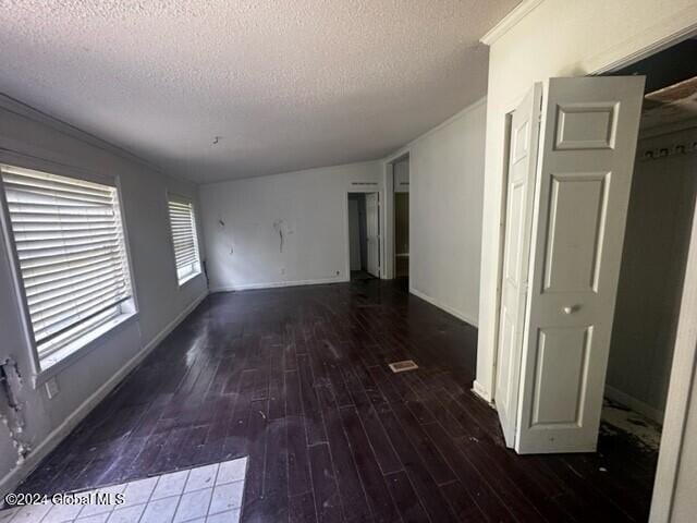 spare room featuring a textured ceiling and dark wood-type flooring