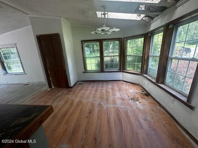 interior space with a chandelier, lofted ceiling, a textured ceiling, hardwood / wood-style flooring, and ornamental molding