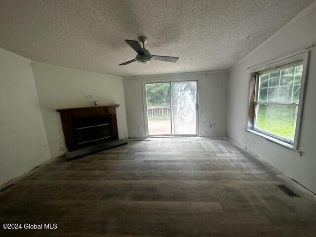 unfurnished living room featuring ceiling fan, dark wood-type flooring, vaulted ceiling, a textured ceiling, and ornamental molding