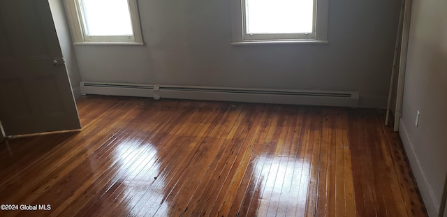 unfurnished room with dark hardwood / wood-style floors and a baseboard heating unit