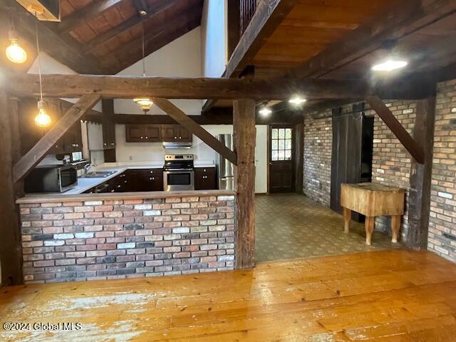 kitchen with stainless steel range with electric stovetop, vaulted ceiling with beams, wood-type flooring, and brick wall