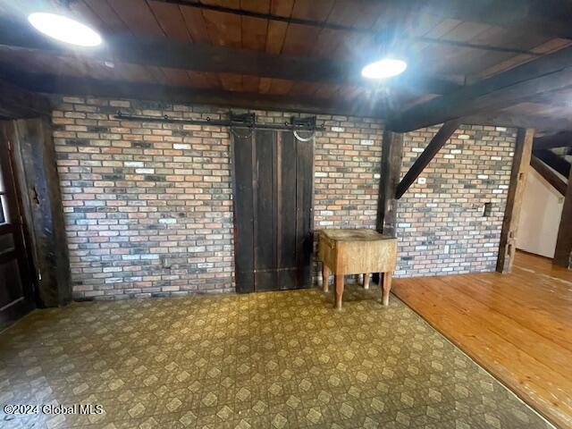 basement with wood-type flooring, wooden ceiling, and brick wall