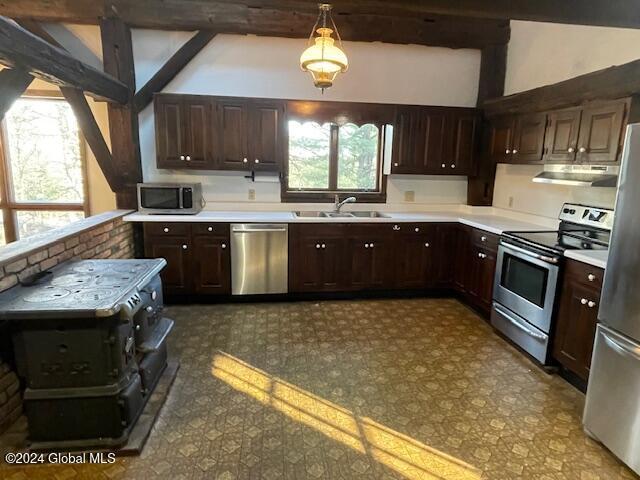 kitchen with sink, lofted ceiling with beams, decorative light fixtures, and appliances with stainless steel finishes