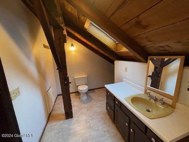 bathroom with lofted ceiling with skylight, vanity, wooden ceiling, and toilet