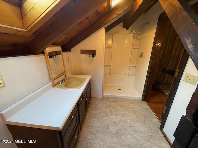 bathroom with vanity, vaulted ceiling, and walk in shower