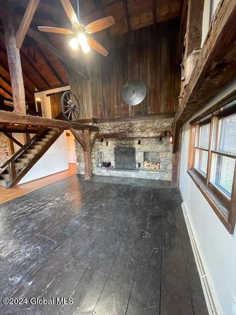 unfurnished living room with vaulted ceiling, ceiling fan, and wooden walls