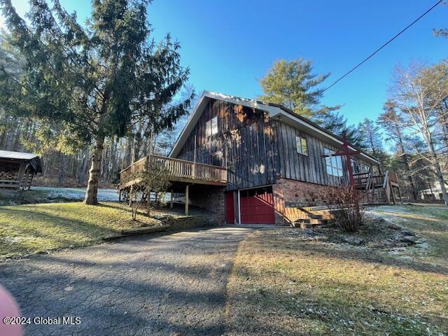 view of property exterior featuring a yard, a garage, and a wooden deck