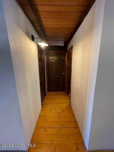 corridor with light wood-type flooring and wood ceiling