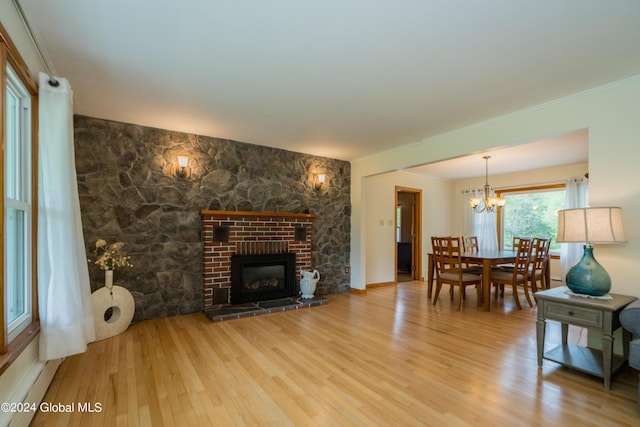 living room with a notable chandelier, wood-type flooring, and a brick fireplace