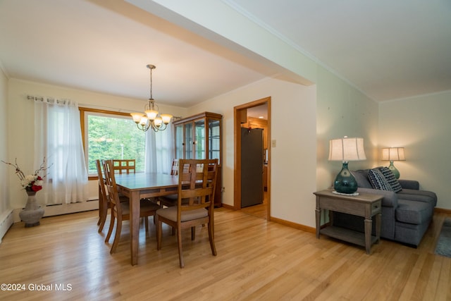 dining space featuring crown molding, light hardwood / wood-style flooring, a baseboard radiator, and an inviting chandelier