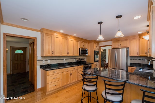 kitchen featuring sink, hanging light fixtures, stainless steel appliances, a breakfast bar area, and light wood-type flooring