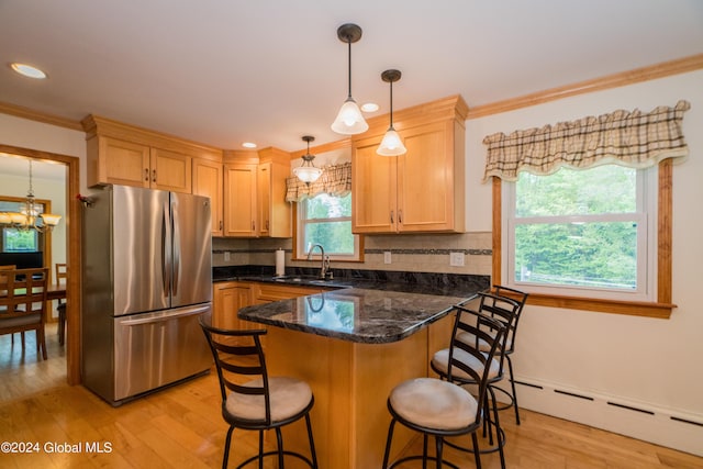 kitchen featuring decorative backsplash, light wood-type flooring, sink, and stainless steel refrigerator