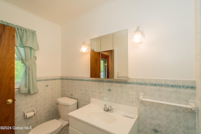 bathroom with vanity, toilet, and tile walls