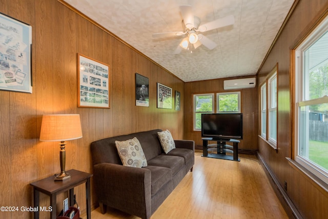 living room with an AC wall unit, wooden walls, plenty of natural light, and light hardwood / wood-style flooring