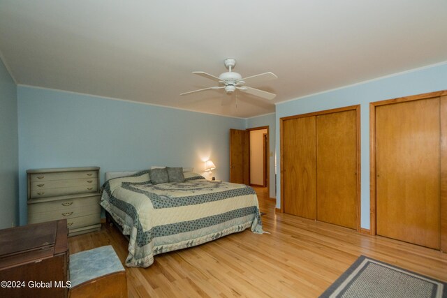 bedroom with light wood-type flooring, two closets, and ceiling fan