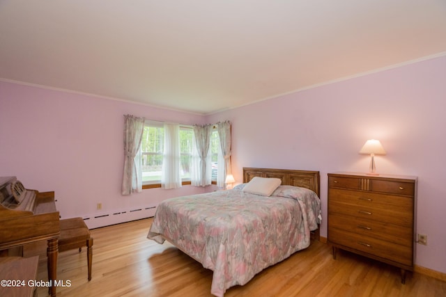 bedroom featuring ornamental molding, light wood-type flooring, and a baseboard heating unit