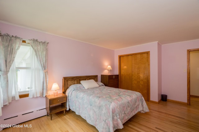 bedroom with a baseboard radiator, light hardwood / wood-style flooring, a closet, and ornamental molding