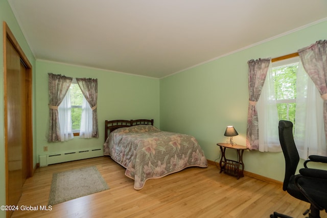 bedroom featuring a closet, a baseboard radiator, hardwood / wood-style flooring, and ornamental molding