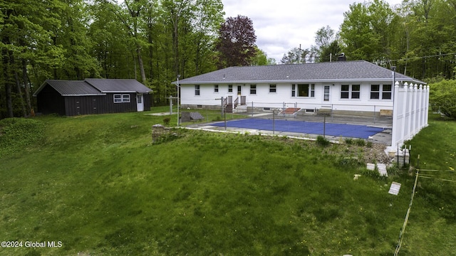 rear view of house with an outdoor structure, a yard, and a covered pool