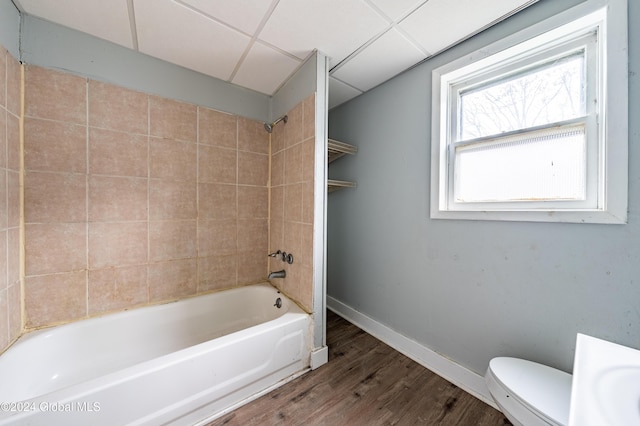 bathroom with toilet, a drop ceiling, tiled shower / bath, and hardwood / wood-style flooring