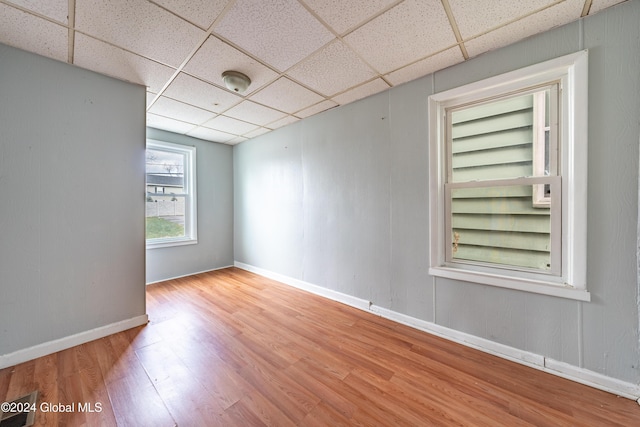 spare room featuring a drop ceiling, built in features, and hardwood / wood-style flooring