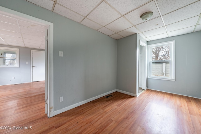 unfurnished room with a drop ceiling, wood-type flooring, and a wealth of natural light