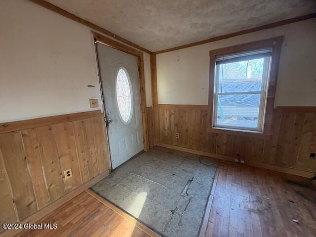 foyer entrance featuring light hardwood / wood-style floors, ornamental molding, and wood walls