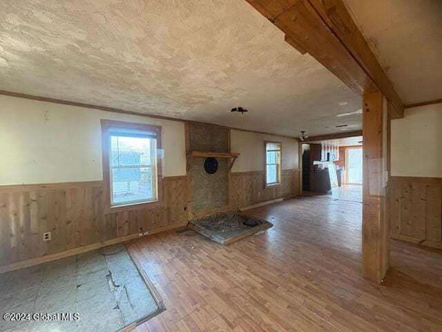 unfurnished living room featuring wooden walls and light hardwood / wood-style floors