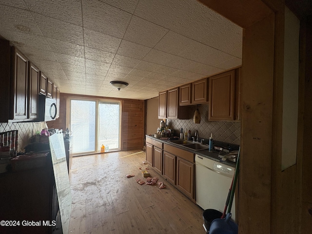 kitchen with backsplash, sink, light hardwood / wood-style floors, and white appliances