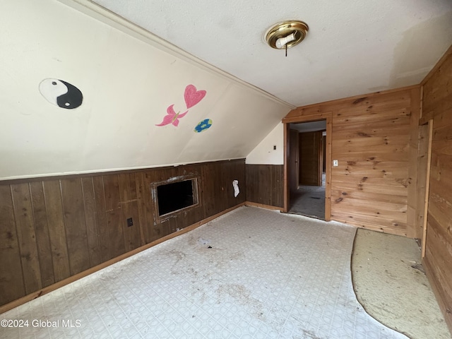 additional living space featuring wooden walls and lofted ceiling