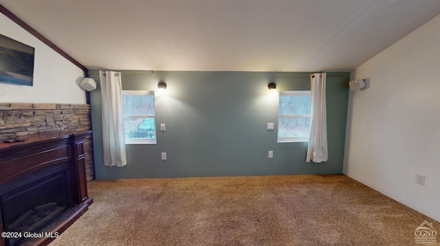 carpeted living room with a stone fireplace