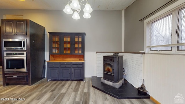 living room with light wood-type flooring, a wood stove, wooden walls, and an inviting chandelier