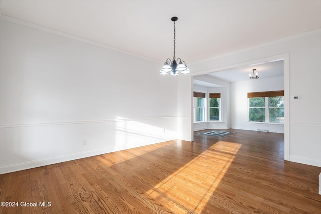 empty room with hardwood / wood-style floors and a chandelier