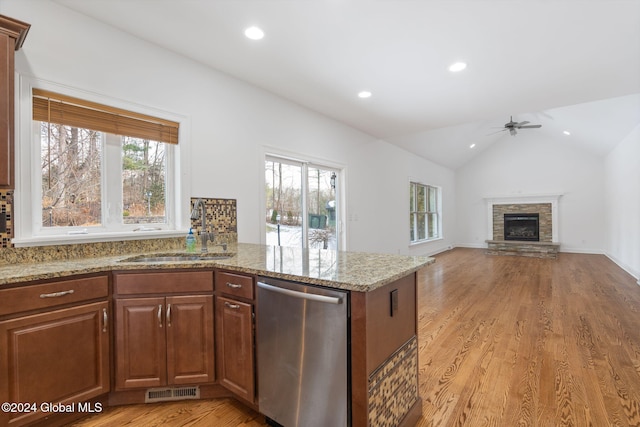 kitchen featuring dishwasher, a stone fireplace, light wood-type flooring, and sink