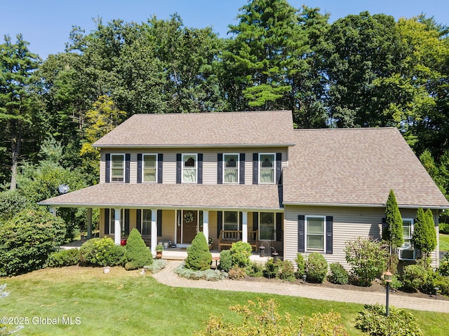 colonial house featuring a front lawn, a porch, and a shingled roof