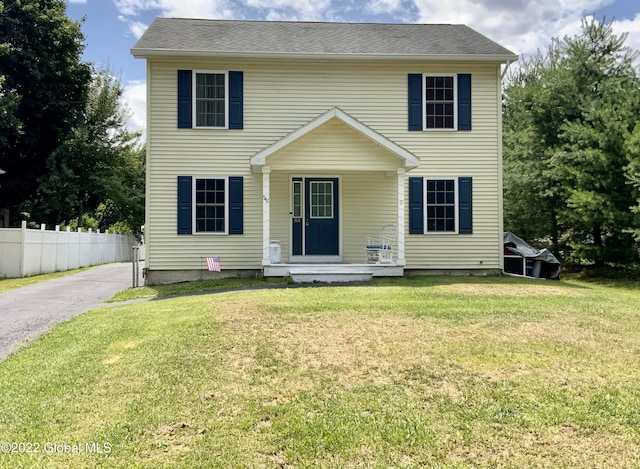 colonial home with covered porch and a front yard