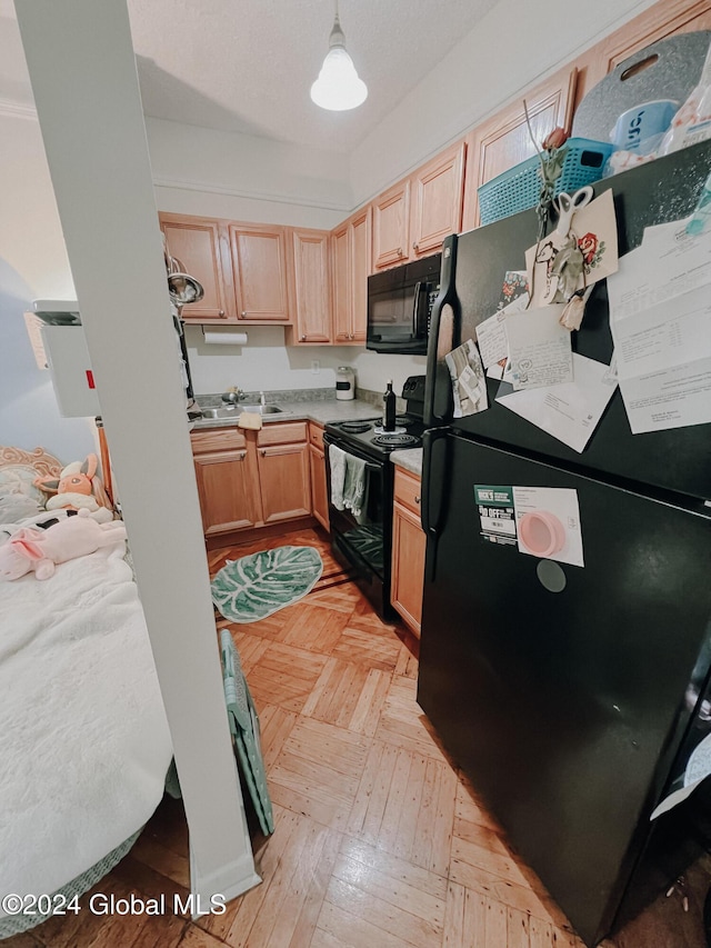 kitchen with pendant lighting, light parquet floors, black appliances, and light brown cabinets