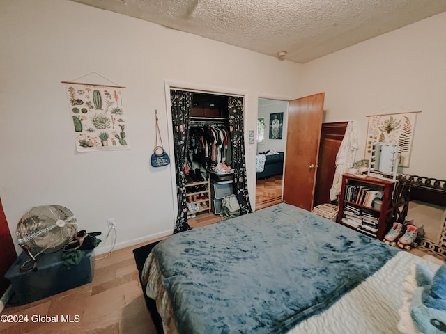 bedroom featuring a closet, light hardwood / wood-style floors, and a textured ceiling