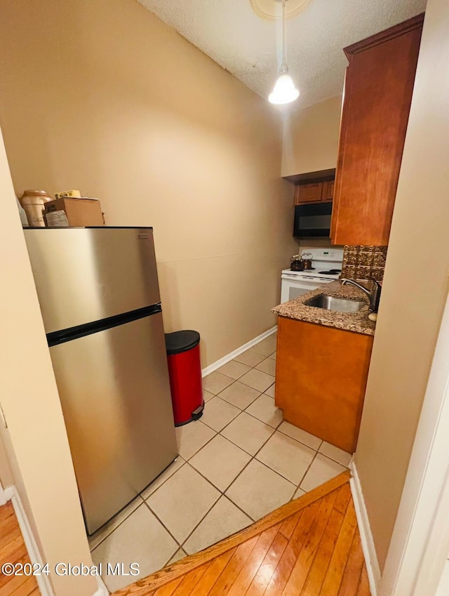 kitchen featuring white stove, sink, stainless steel fridge, a textured ceiling, and light hardwood / wood-style floors