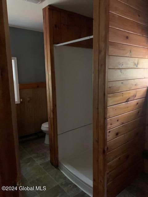 bathroom with toilet, a shower, and wooden walls