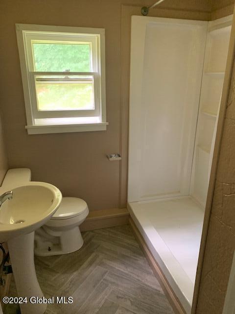 bathroom featuring toilet, parquet flooring, and walk in shower