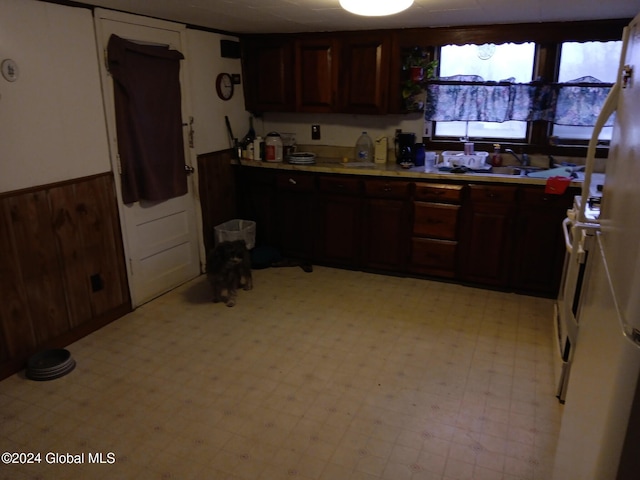 kitchen with wood walls, dark brown cabinetry, and sink